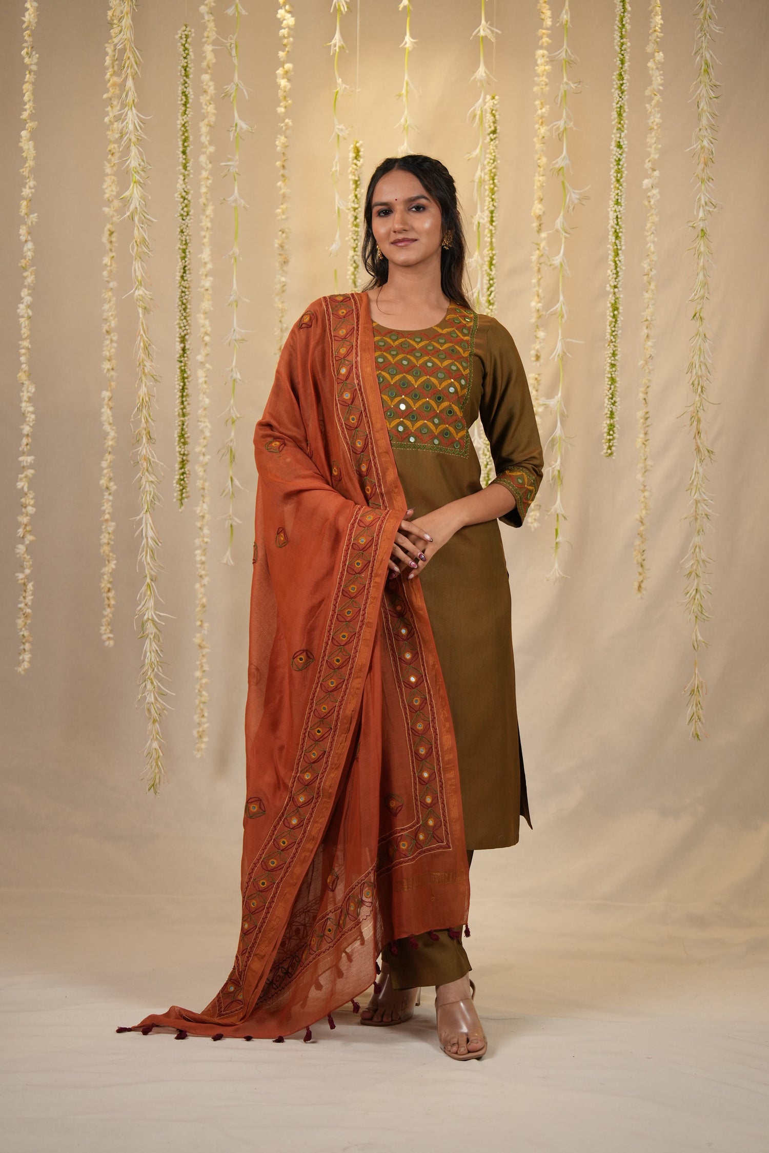Woman holding a traditional saree against a decorative background